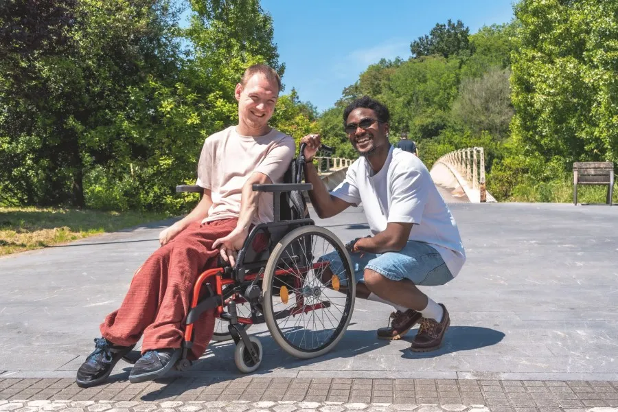 Disabled man in wheelchair smiling with support worker